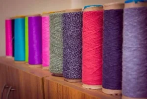 Cones of recycled knitting yarn in mixed colours on a shelf